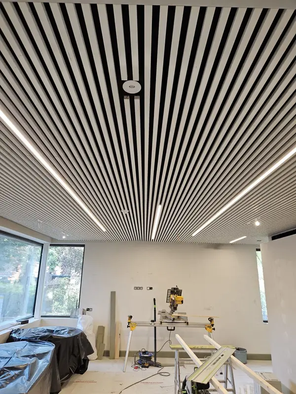 Lattenplafond met lange lichtlijnen ertussen, in een ruimte die nog in afwerking is