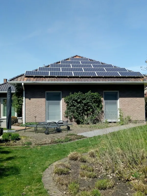 Bungalow met zonnepanelen op twee dakvlakken, met een tuin ervoor